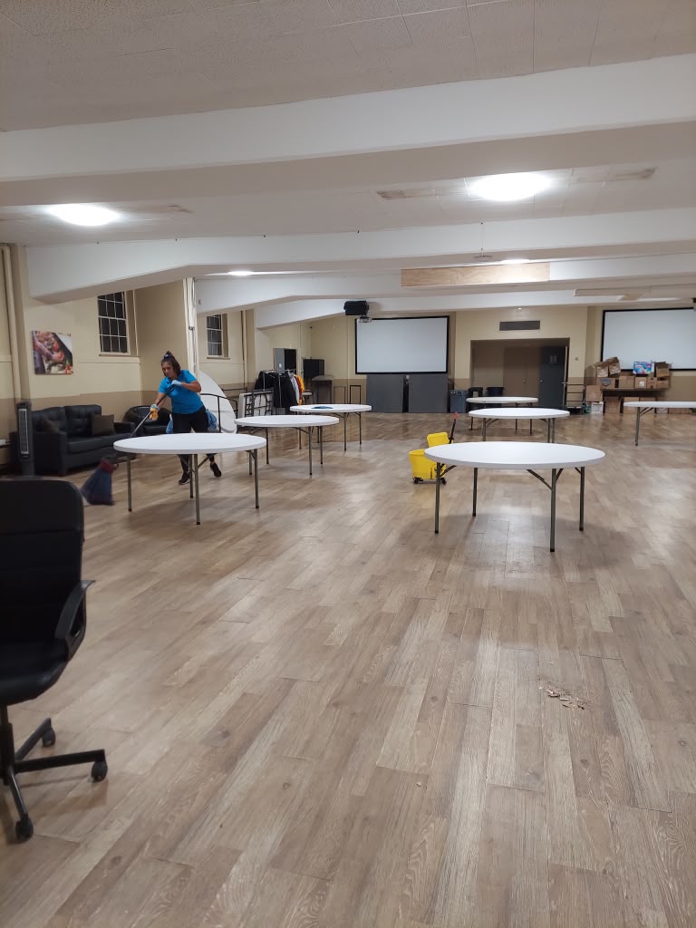 Two Franco's crew members cleaning tables and floors in a community hall